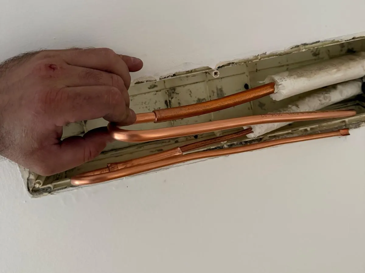 Tubi in rame di un condizionatore modificati con una curva saldata, dentro la canalina nel muro