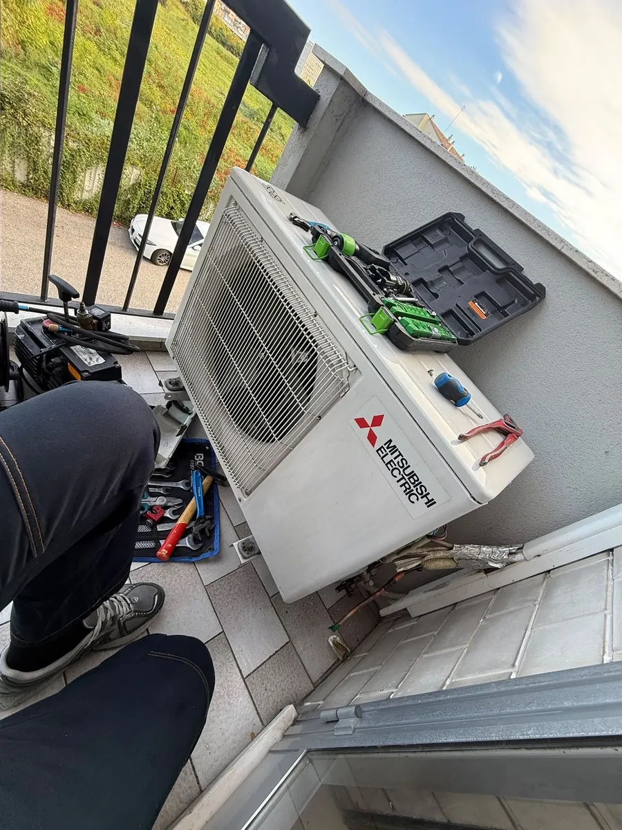 Unità esterna di un condizionatore Mitsubishi Electric su un balcone, con gli attrezzi del tecnico appoggiati sopra